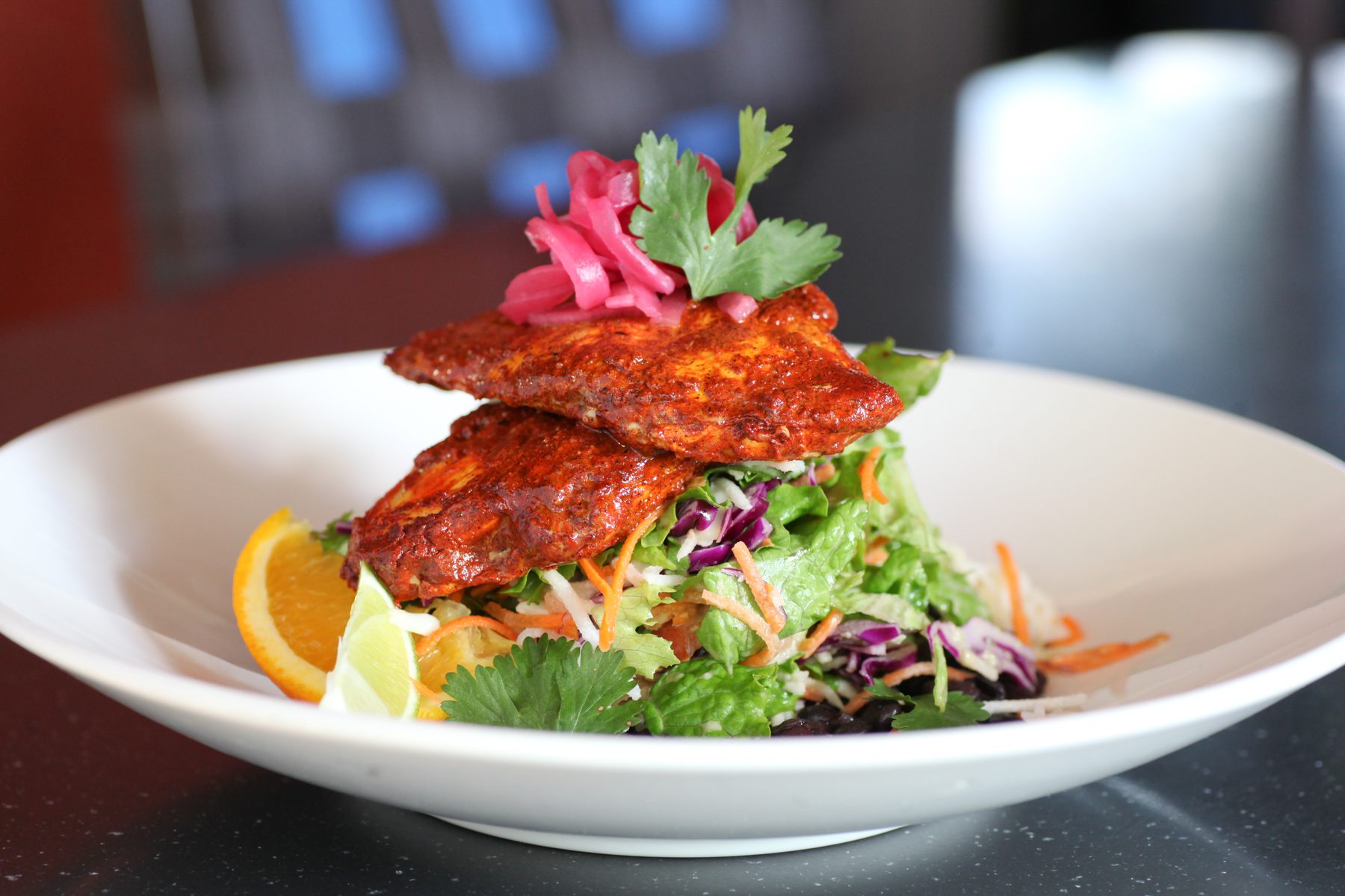 Ensalada con pollo achiote — chargrilled achiote chicken over garden salad with pickled onion and citrus