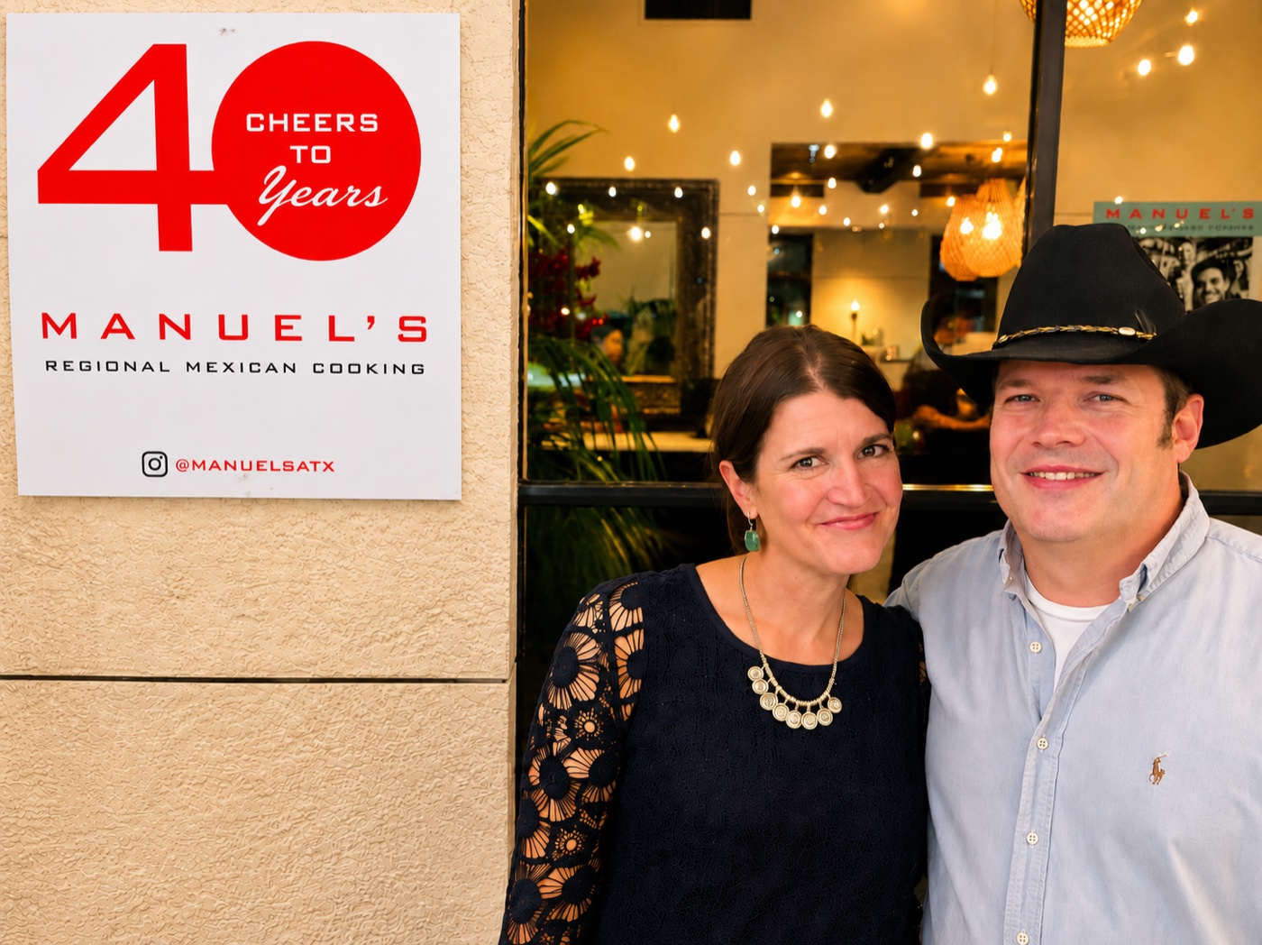 A couple celebrating beside Manuel's Cheers to 40 Years sign outside the restaurant
