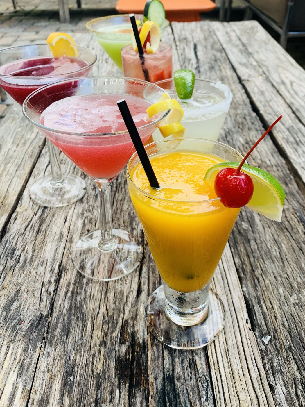 A colorful lineup of margaritas and cocktails on a rustic patio table at Manuel's