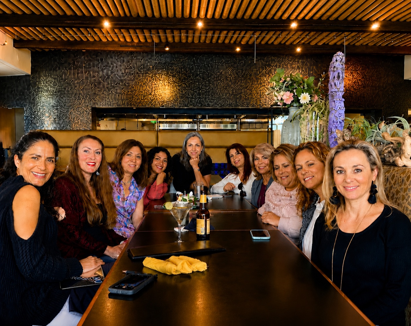 A big group of friends gathered with cocktails around a long table in Manuel's dining room