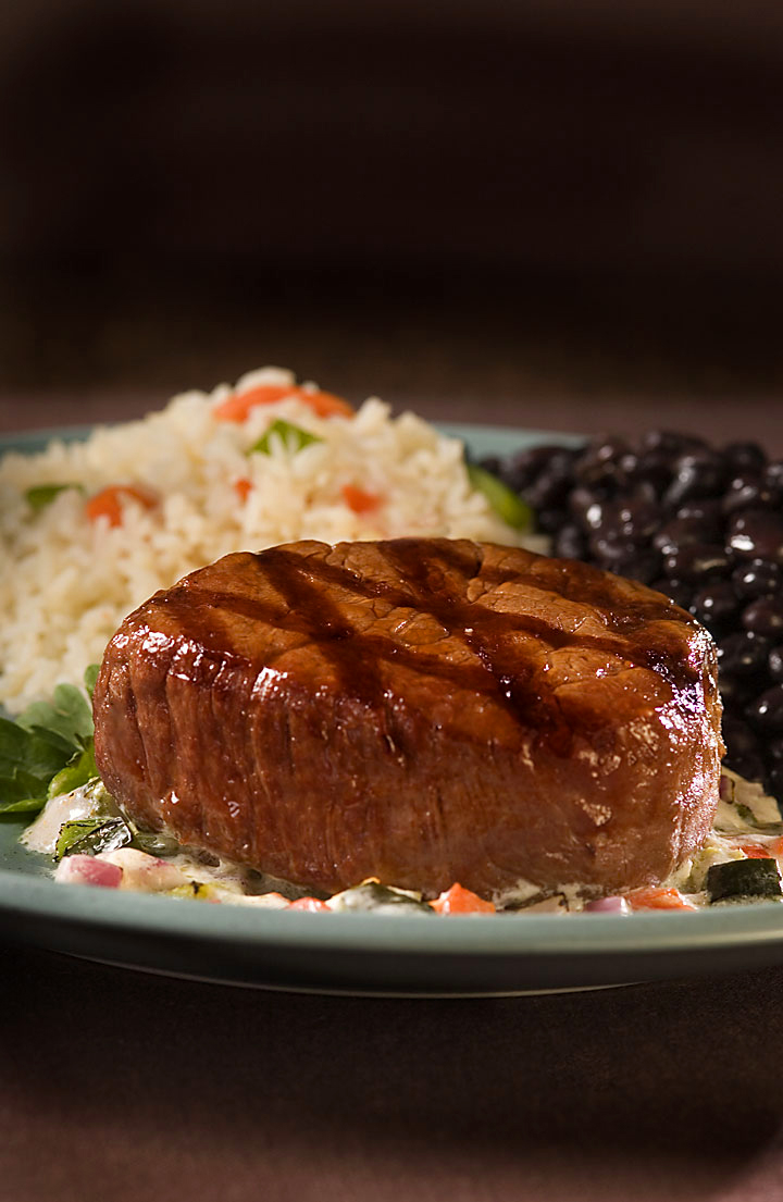 Grilled beef tenderloin with grill marks over Mexican rice, black beans and roasted-vegetable cream