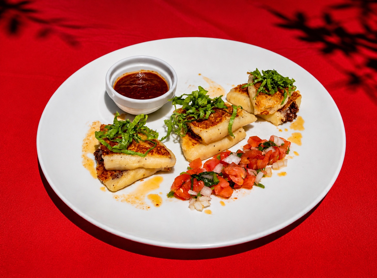 Tortas de Papa y Masa — golden pan-seared potato-and-masa cakes topped with shredded basil, served with pico de gallo and a smoky chile sauce