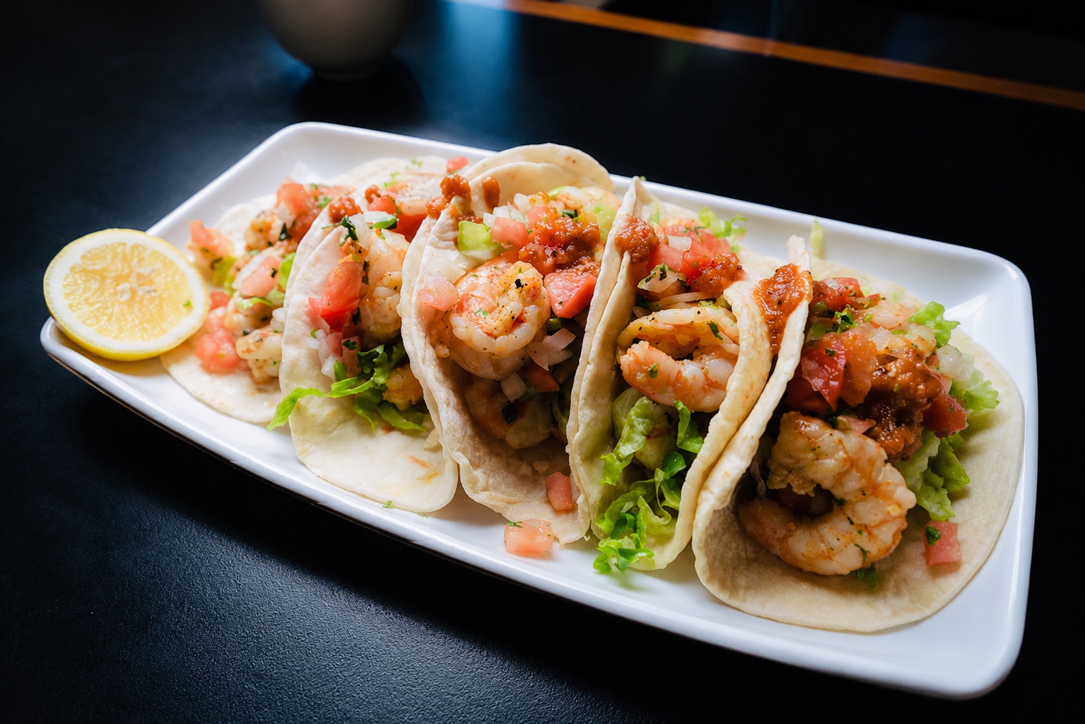 Shrimp tacos on house-made flour tortillas with lettuce, pico de gallo and salsa, with lemon